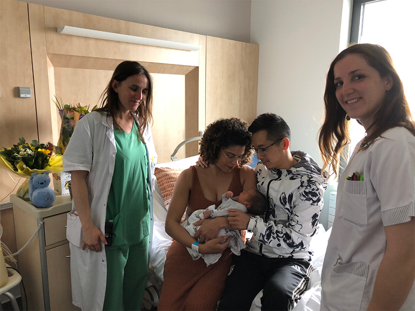 Dans une chambre d'hôpital, un couple tient leur nouveau né dans les bras. Ils sont entourés de personnel du CHD.